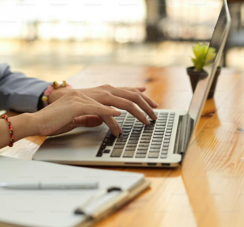 Hands typing on a laptop keyboard